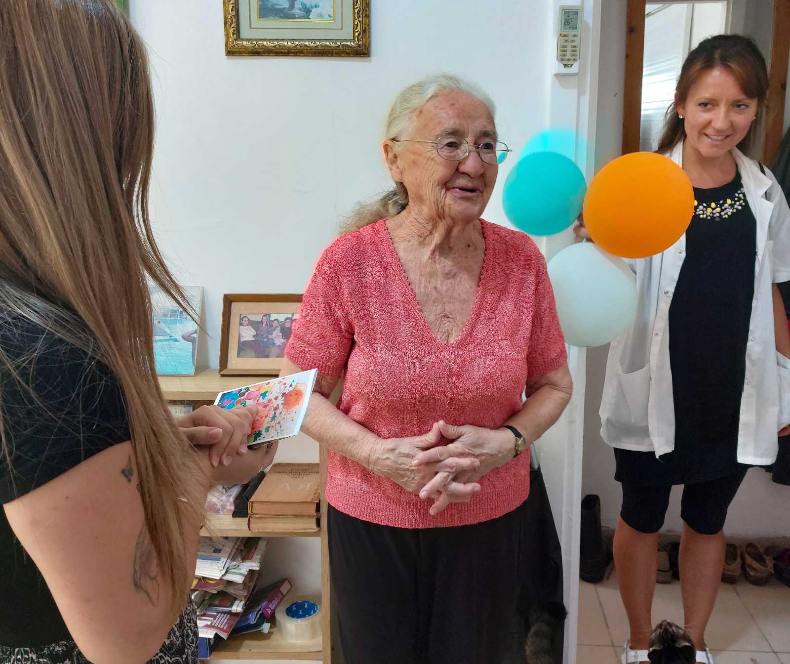 Dankbar und barmherzig - eine alte Damen mit langem Haar lächelt, zwei jüngere Frauen sind bei ihr