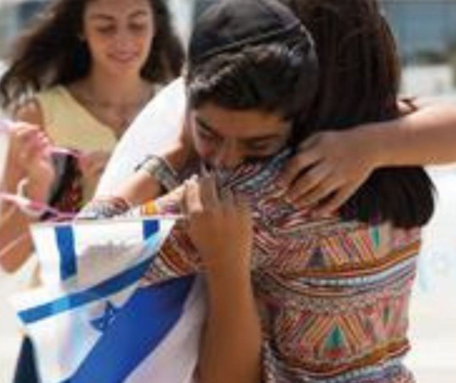 zwei Menschen liegen sich in den Armen. Eine Person hat eine Israel Fahne in der Hand