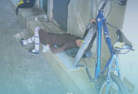 Hilfszentrum Roter Teppich - in einem Hof liegt eine Peerson erschöpft auf dem Boden, neben ihr steht ein Fahrrad