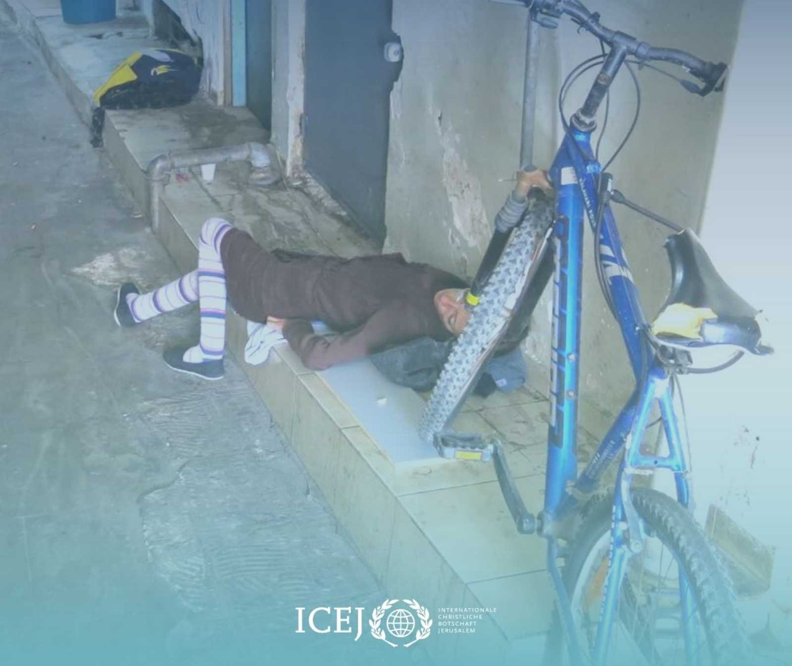 Hilfszentrum Roter Teppich - in einem Hof liegt eine Peerson erschöpft auf dem Boden, neben ihr steht ein Fahrrad