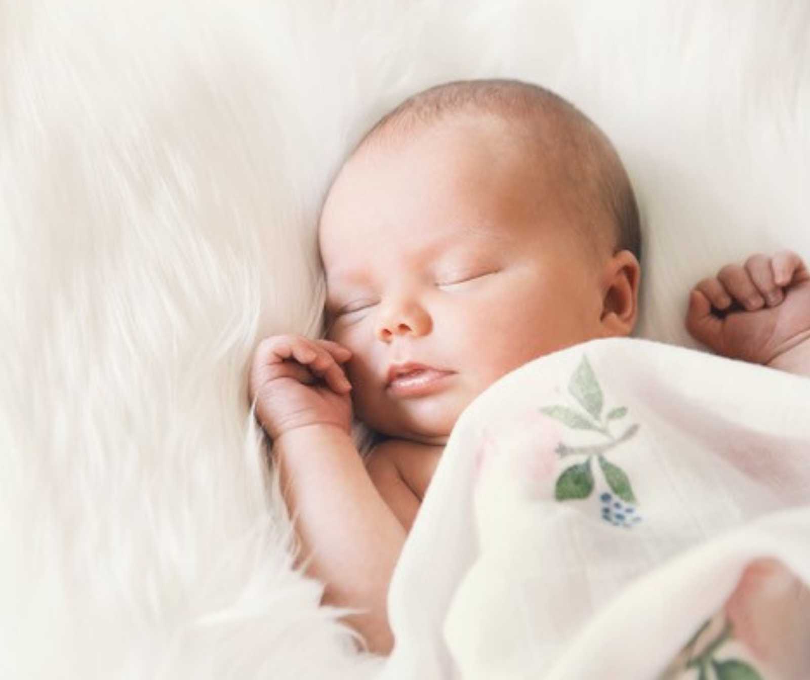 ein schlafendes Baby auf einem Fell liegend