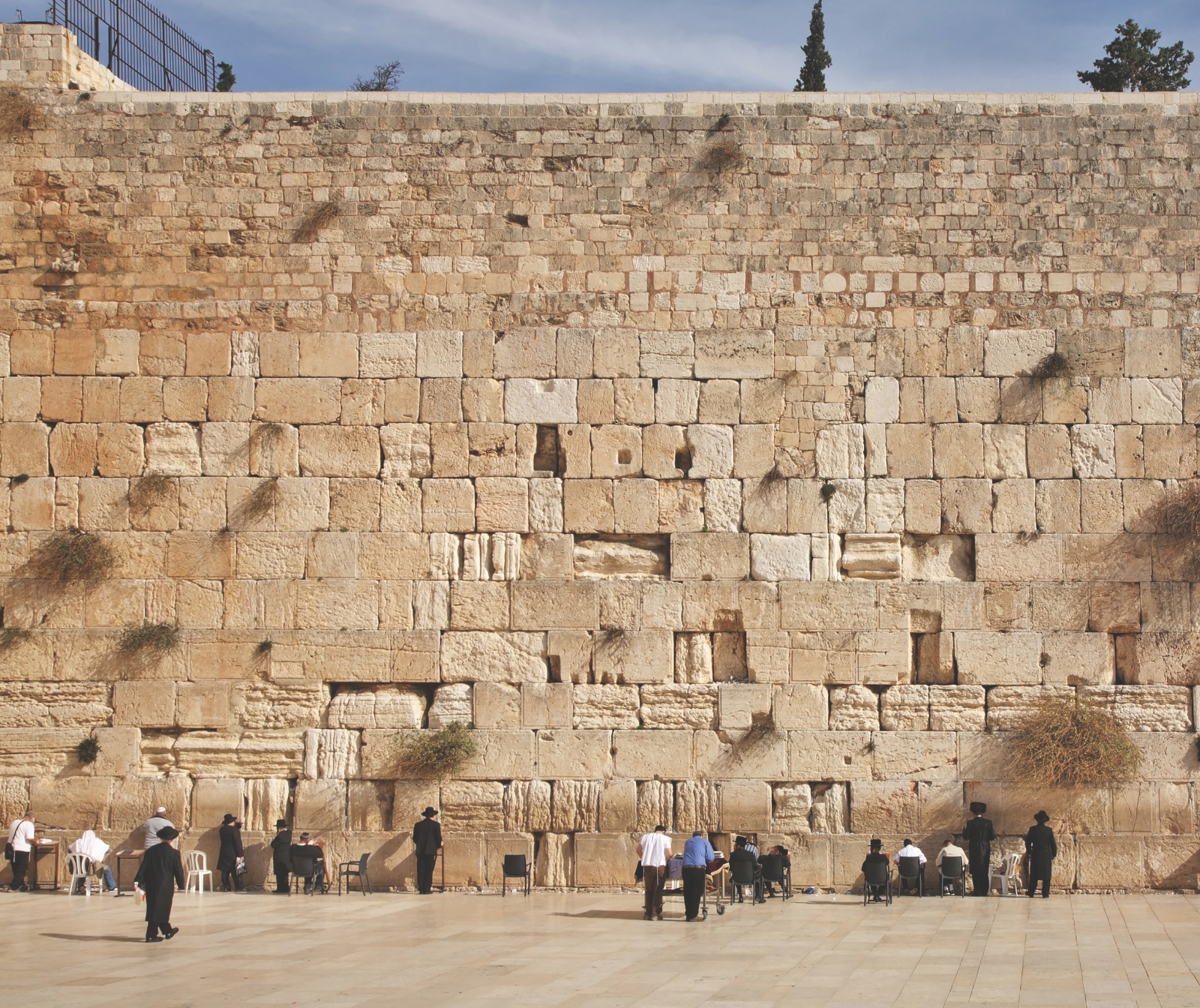 Klagemauer in Jersalem eine Mauer am Platz des Tempelberges mit Steinen und davor Menschen die beten