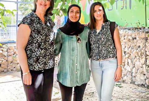 Raum für Frieden schaffen - drei Frauen unterschiedlicher Nationalität stehen nebeneinander, haben ihre Arme hinter den Rücken miteinander verbunden, lächeln in die Kamera