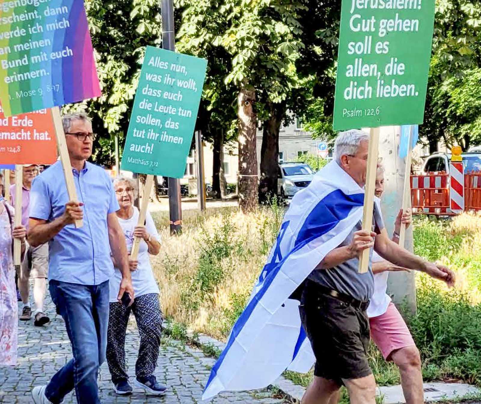 Gebetsmarsch in Stuttgart. Menschen laufen mit Israelflagge und Schildern auf einer Straße