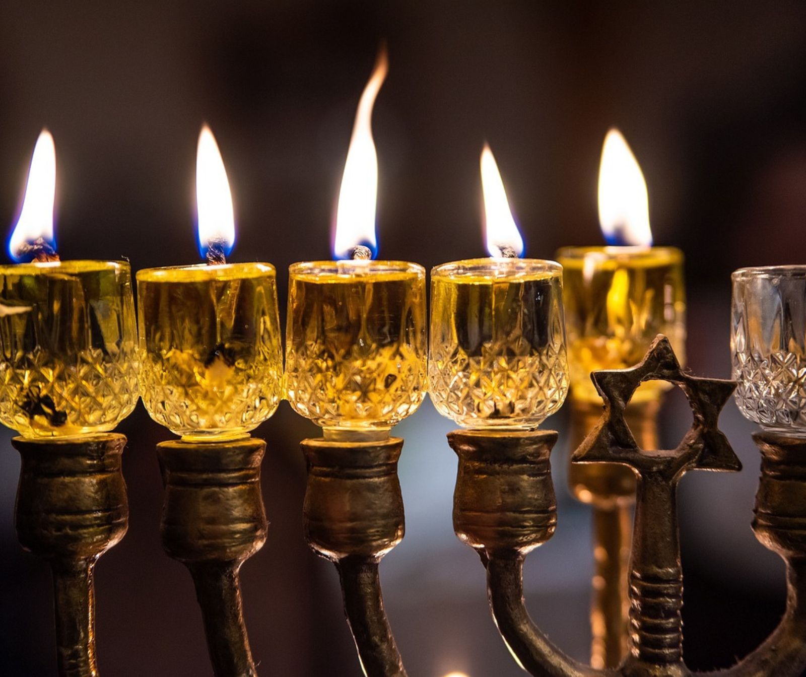Fünf Kerzen am Leuchter brennen zu Chanukka. In der Mitte des Leuchter ist ein Davidstern.