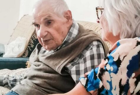 ein alter Mann und eine ältere Dame auf einem Sofa sitzens.