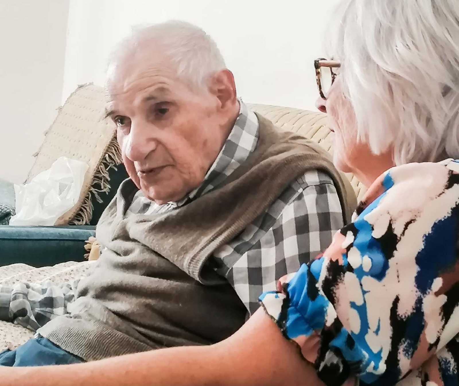 ein alter Mann und eine ältere Dame auf einem Sofa sitzens.