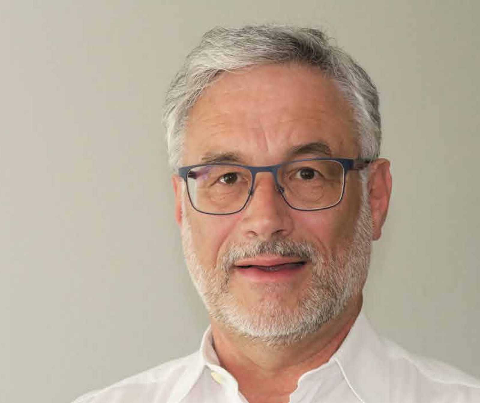 Portraitfoto eines Mannes mit Bart, grauen Haaren und einer Brille