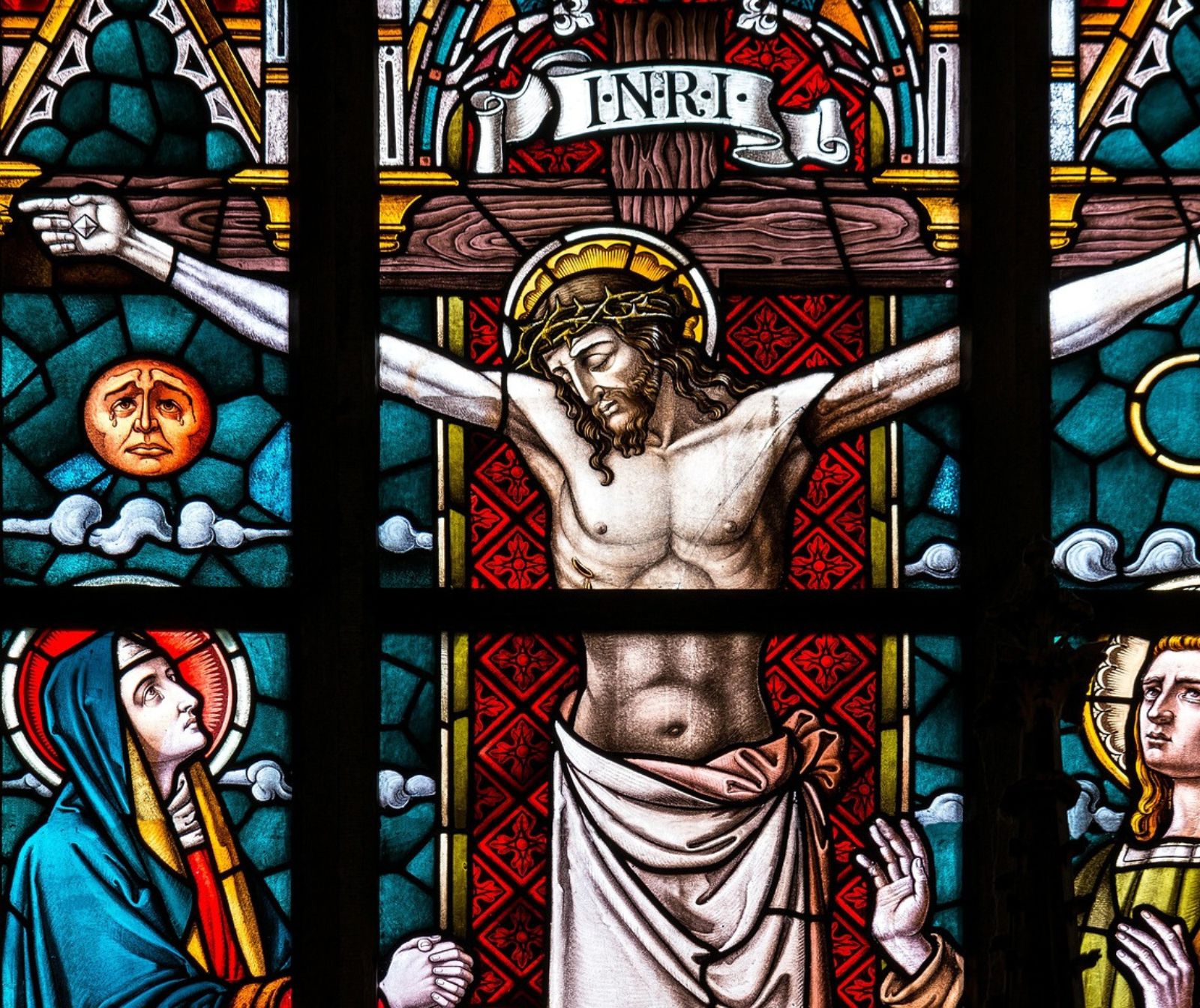 Ein Buntglasfenster in einer Kirche zeigt die Kreuzigung Jesu.