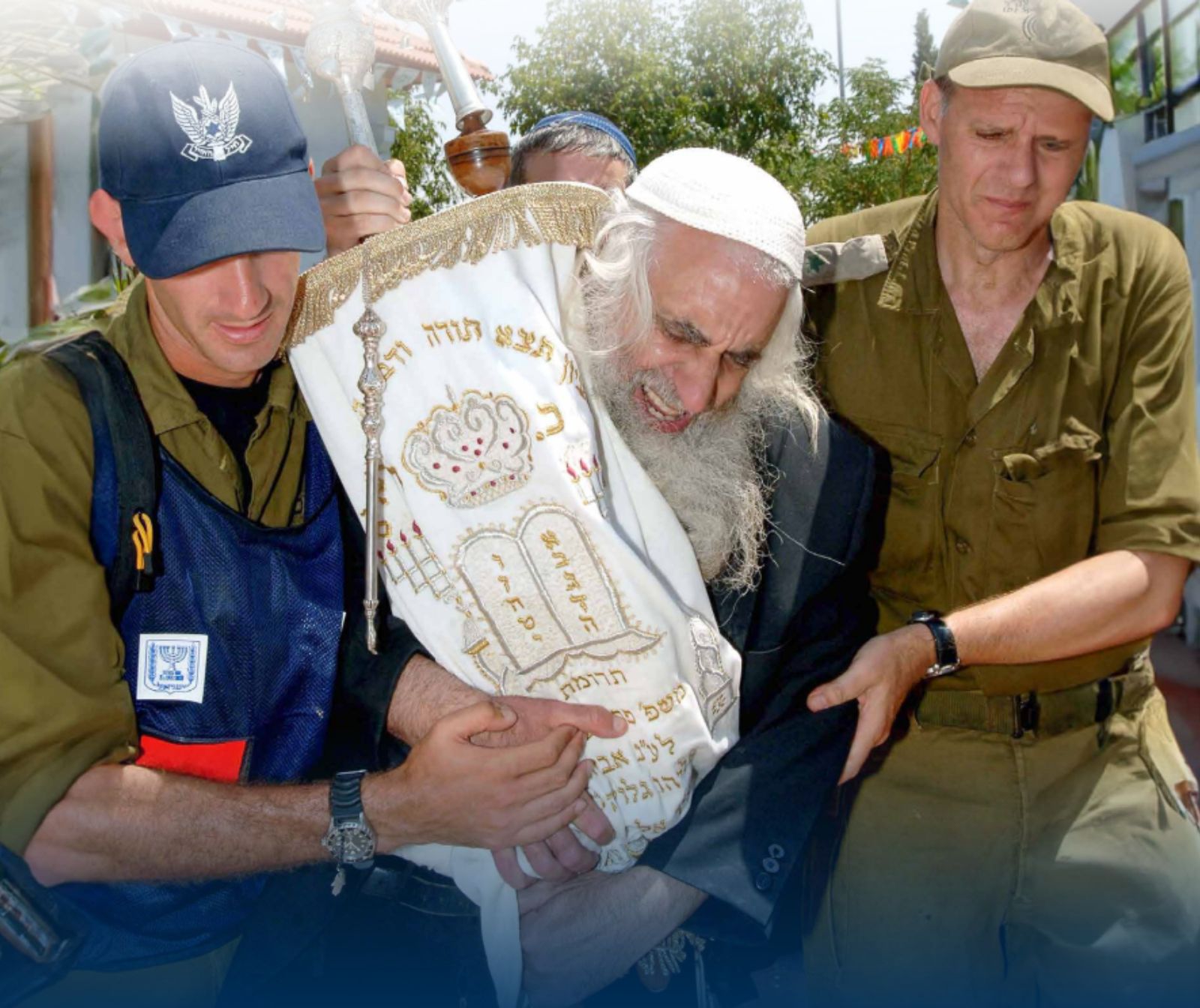 Ein alter Rabbiner umklammert eine Tora-Rolle. Zwei Männer in Olivgrüner Uniform halten den Mann am Arm und führen ihn. Das Gesicht des Rabbiners ist schmerzzerrissen.