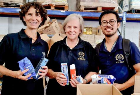 Zwei Frauen und ein Mann nebeneinanderstehend und in die Kamera lächelnd. Sie halten verschieden Produkte, u.a. Zahnpasta in der Hand