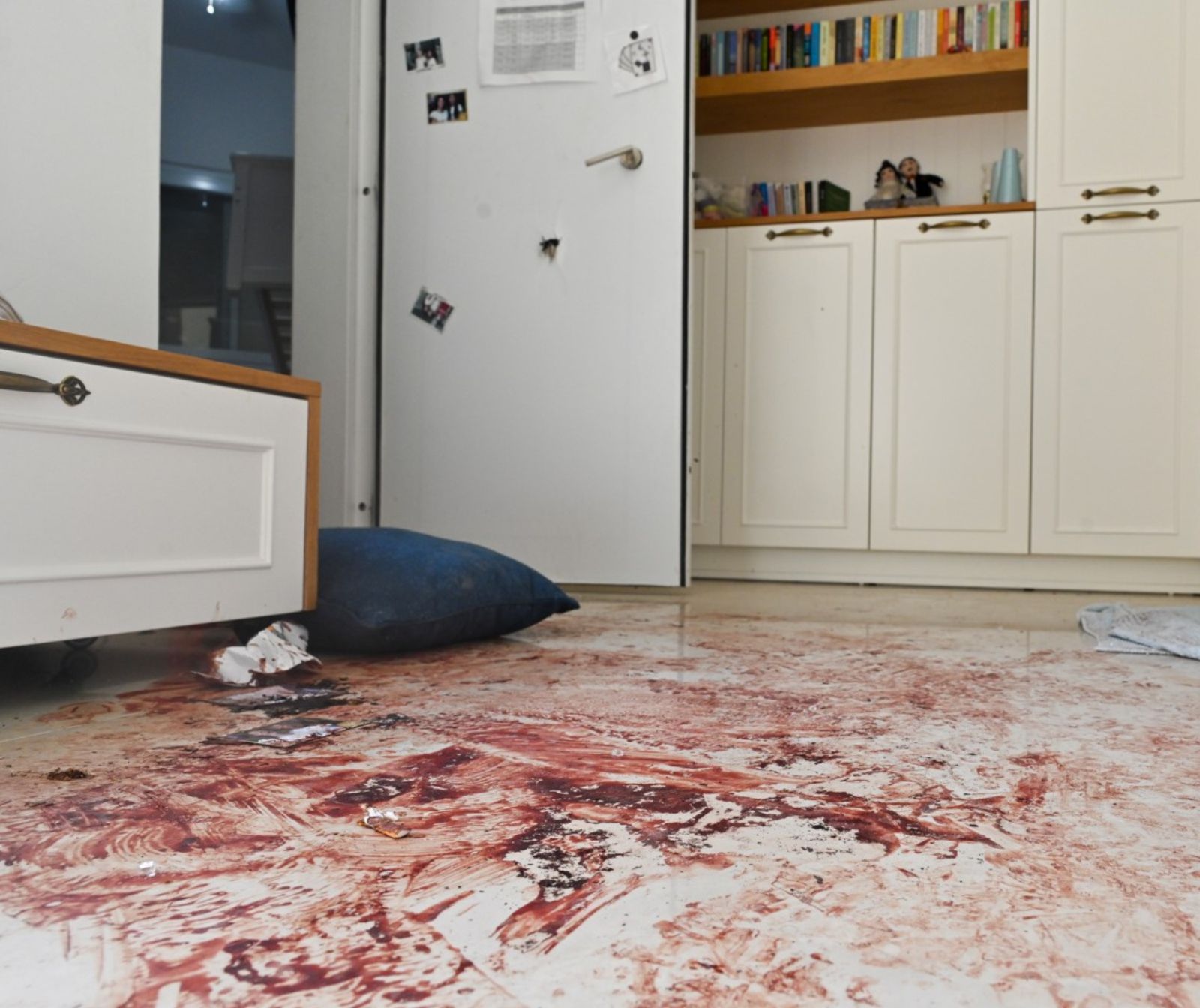 Ein Wohnzimmer im Kibbuz Nahal Oz. Der weiße Boden ist blutverschmiert, in der Zimmertüre ist ein Einschussloch.