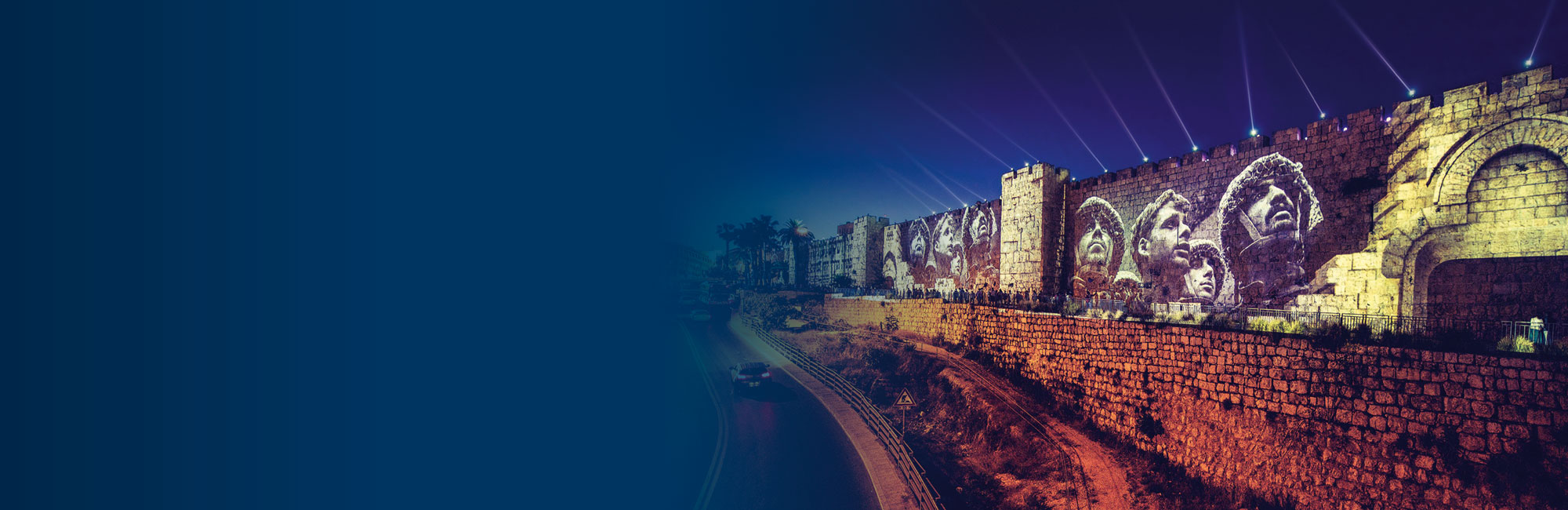 Altstadtmauern von Jerusalem werden mit Lichtshow beleuchtet darauf Gesichter