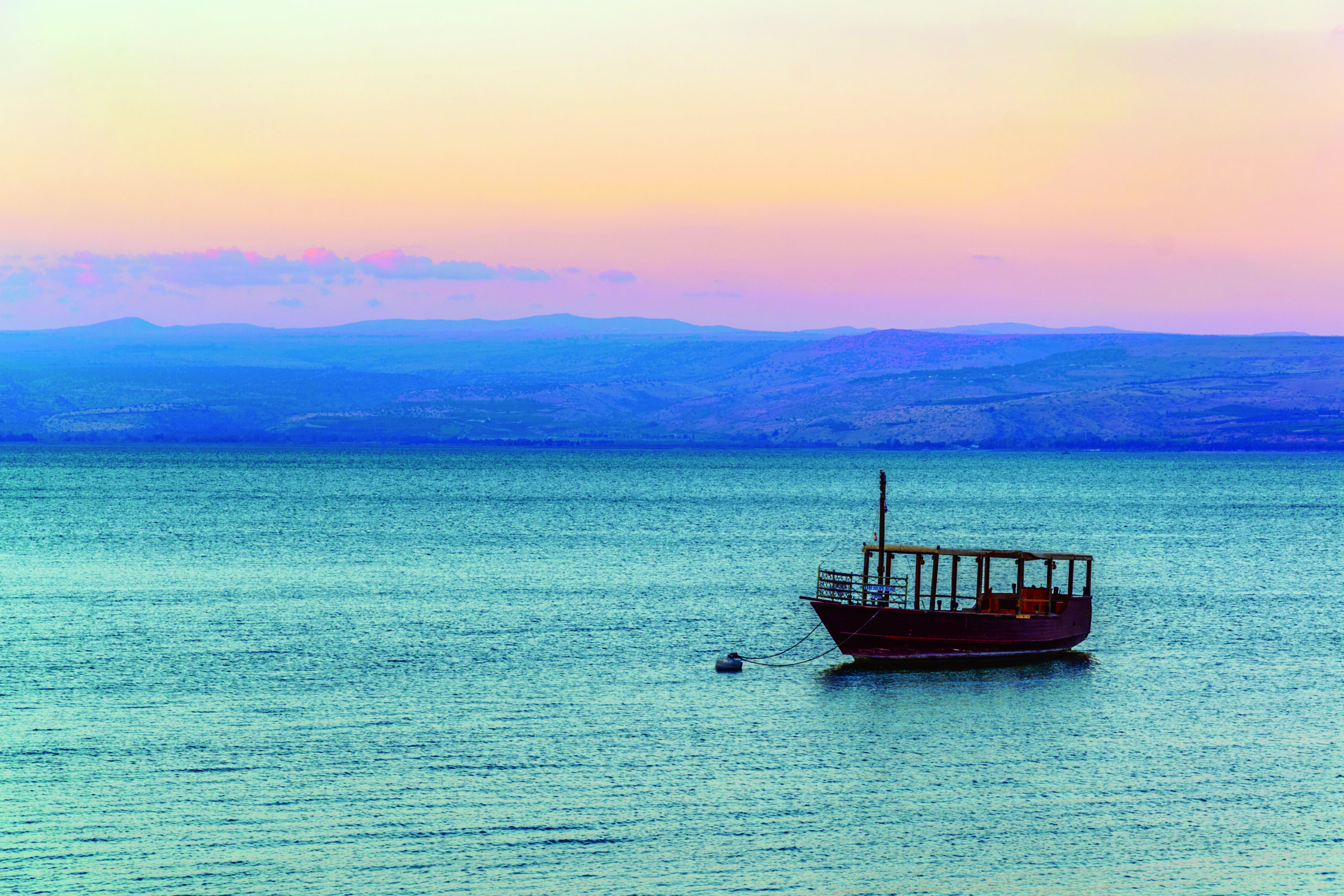 Sunset view of a wooden boat floating on the sea of galilee, Isr