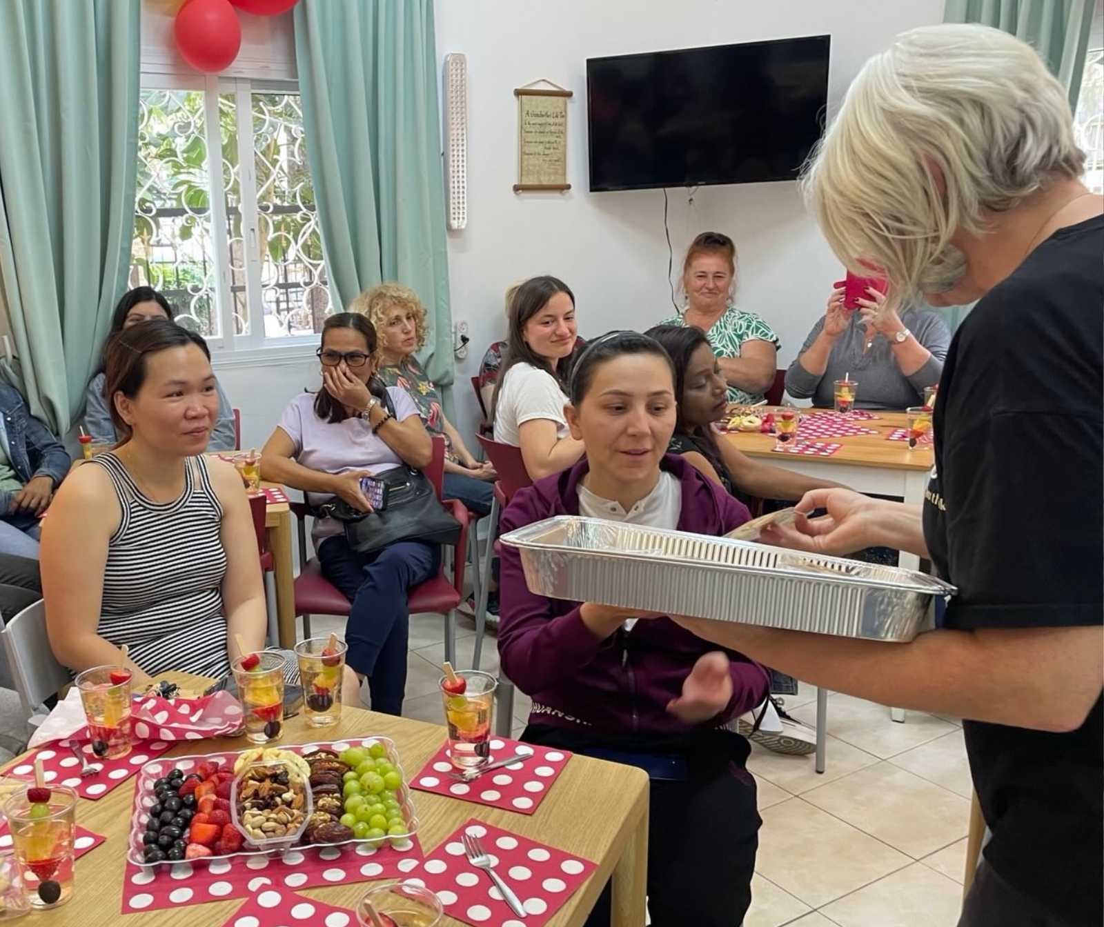 In einem Aufenthaltsraum sitzen an verschiedenen Tischen Menschen unterschiedlichen Alters und Nationalität und genießen essen und trinken