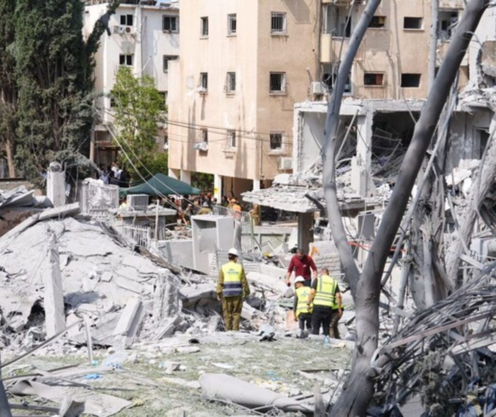 In den Trümmern eines Gebäudes stehen mehrere Menschen mit Sicherheitswesten