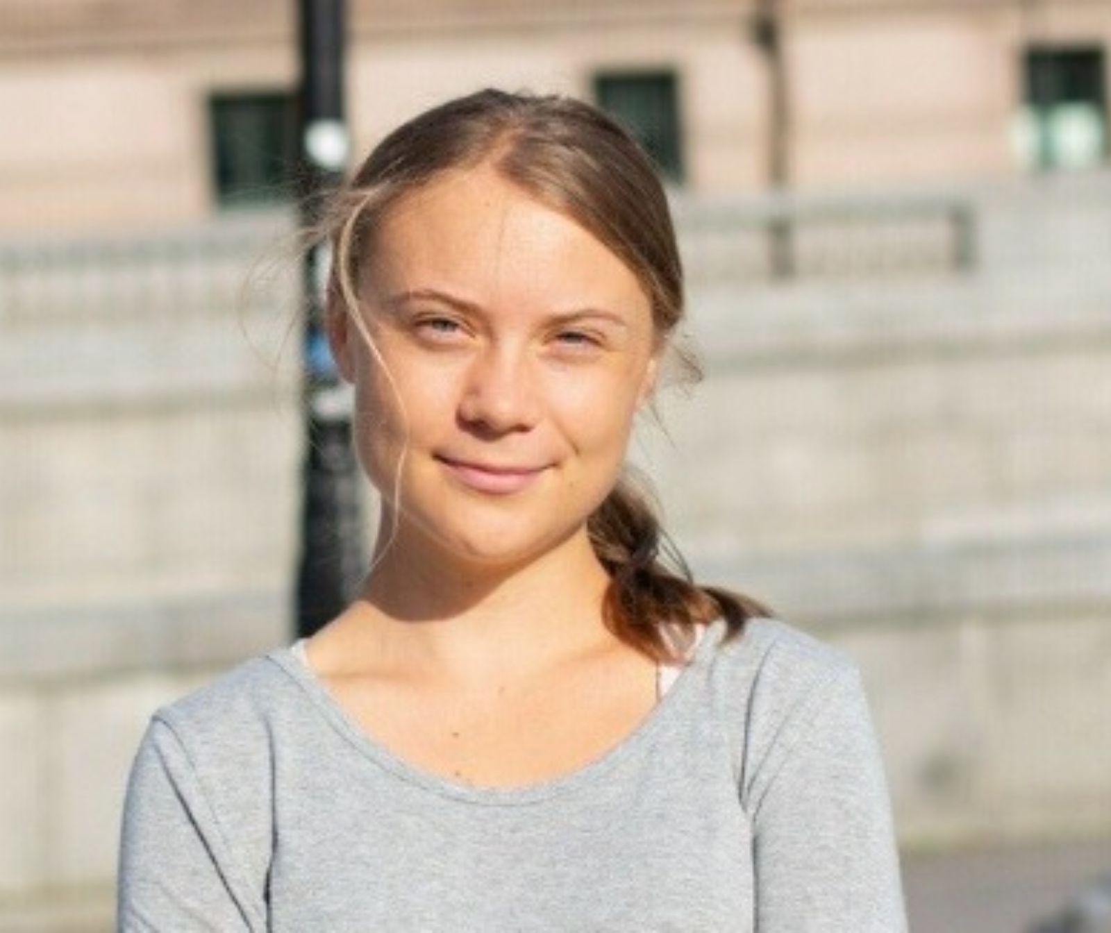 Greta Thunberg, mit schulterlangen, blonden Haare und einem grauen Oberteil blickt in die Kamera