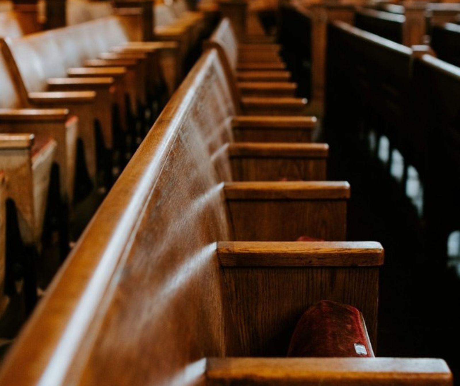 Leere Kirchenbänke aus hellem Holz.