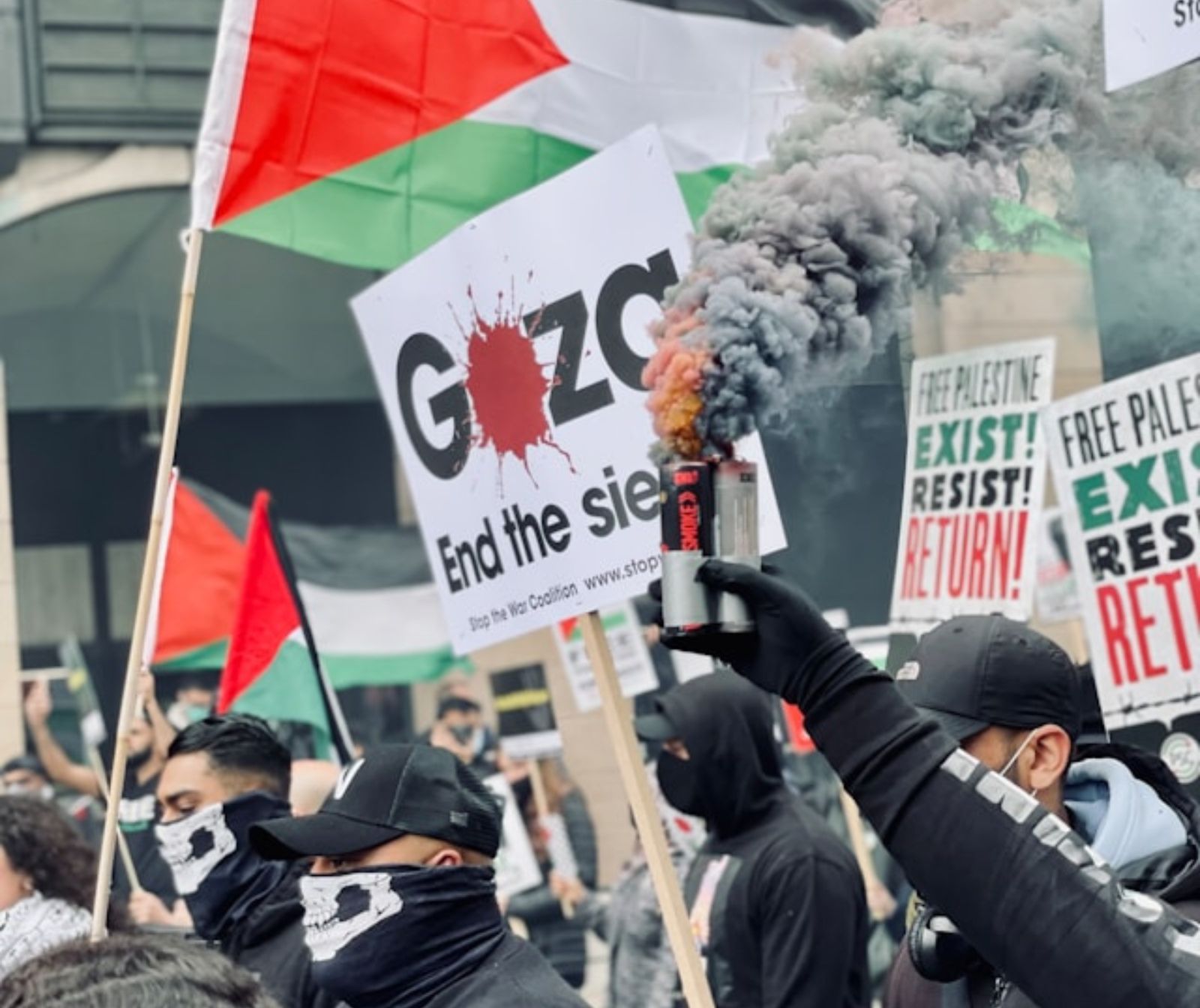 Kein Kegelclub, sondern Terrorbanden. Eine Gruppe schwarz gekleideter Personen hält Palästina-Flaggen in die Luft und eine rauchende Dose.