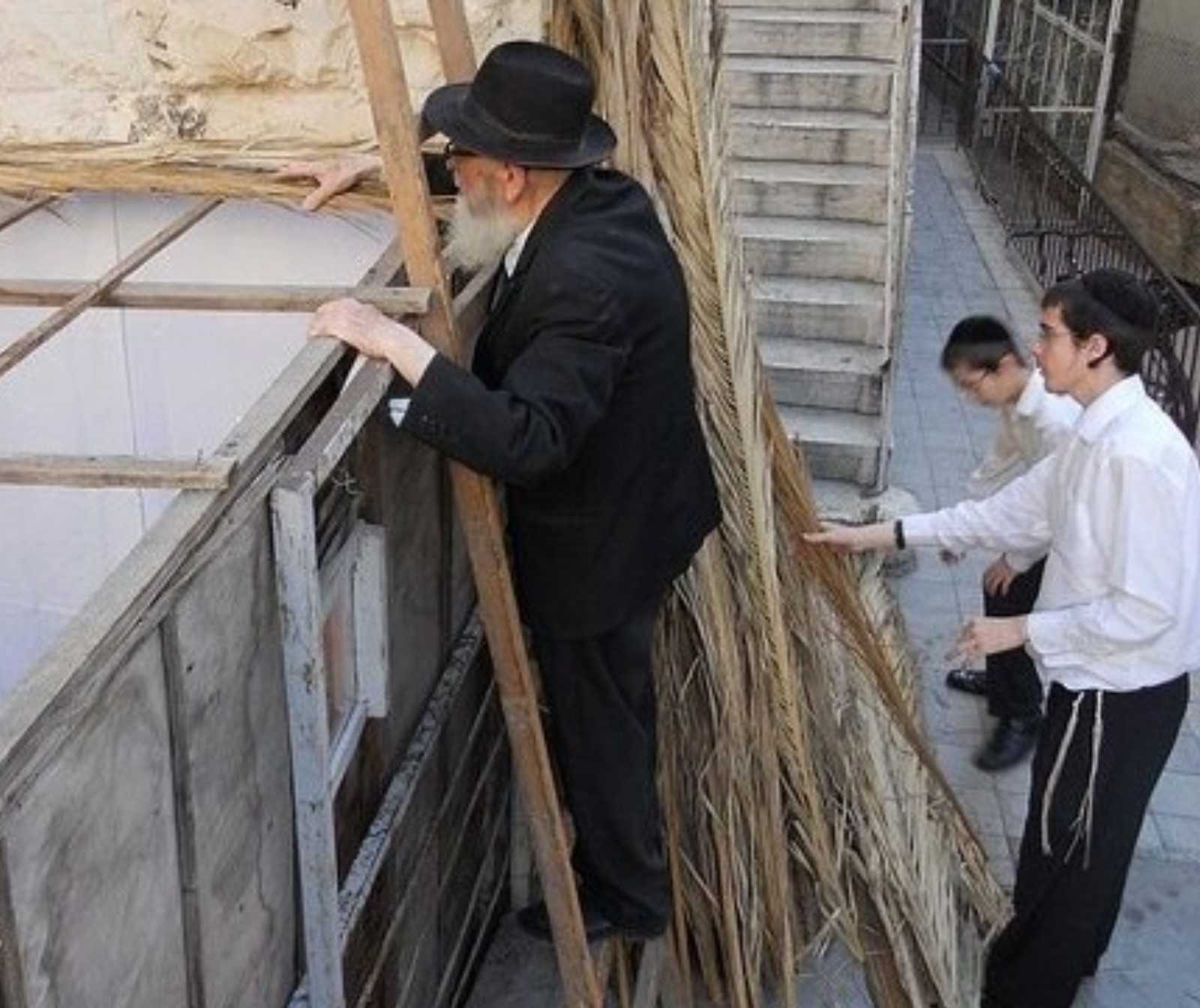 Rabbi mit Hammer und Nägeln - ein Rabbi steht oben auf einer Leiter an einer Holzhütte