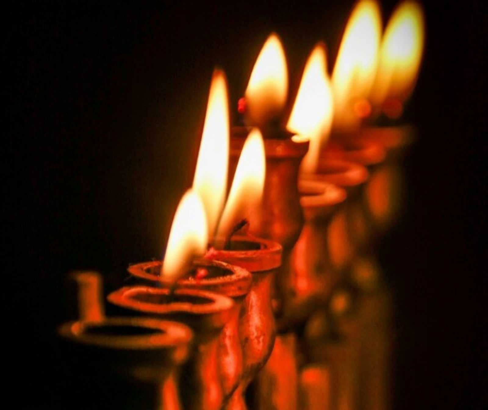 ein mehrarmiger Kerzenleuchter, dessen Kerzen runtergebrannt sind, nur noch Docht und Flamme sind zu sehen