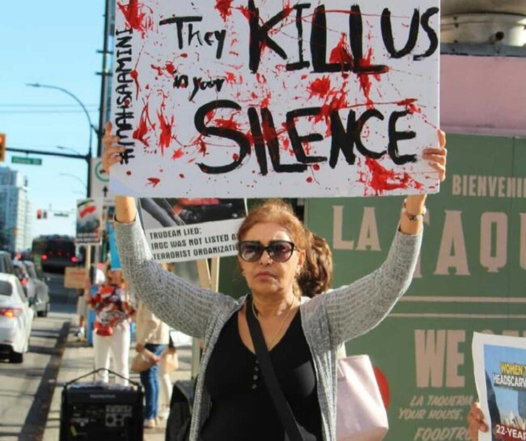 eine Frau mit Sonnenbrille hält ein schild über ihrem Kopf. es sit zu lesen: They kill usto your silence