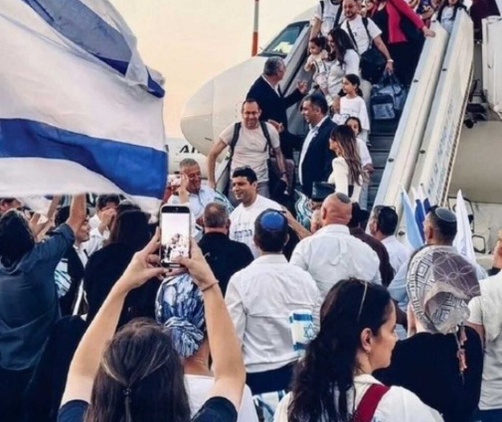 aus einem Flugzeug steigen Menschen aus. Ein Frau macht Fotos mit ihrem Handy. Manche Männer tragen eine Kippa