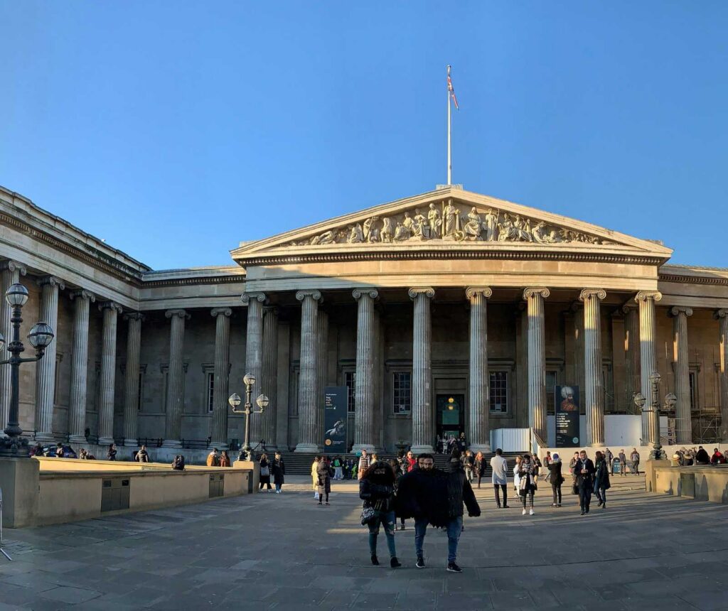 ein Gebäude mit klassischer Säulenfassade und Besuchern davor