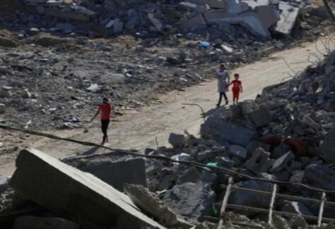 Zivilisten, darunter ein kind, laufen durch ein Gebiet mit Gebäudetrümmern