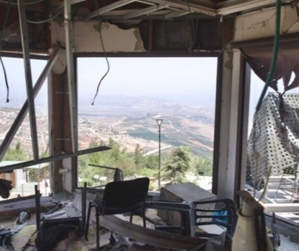 der Blick nach draußen durch ein Fenster. Das Gebäude ist zerstört, es liegen überall Trümmer herum, das Fensterglas nicht mehr vorhanden.