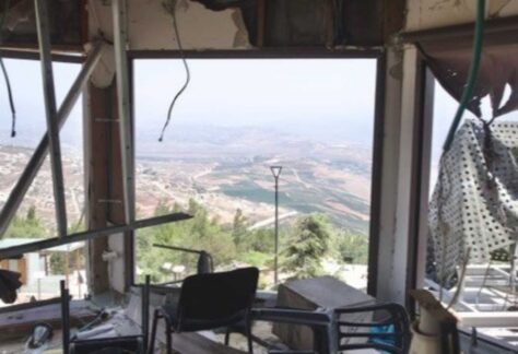 der Blick nach draußen durch ein Fenster. Das Gebäude ist zerstört, es liegen überall Trümmer herum, das Fensterglas nicht mehr vorhanden.