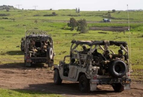 drei militärische Geländewagen, die hintereinander durch ein grünes Gelände fahren