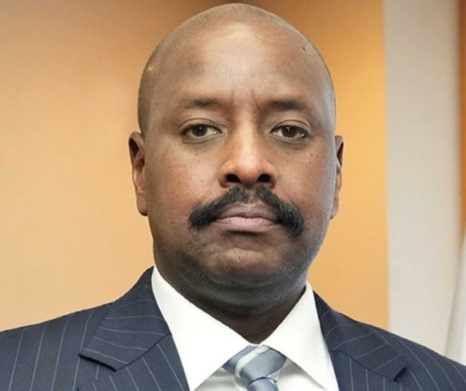 Portraitfoto eines dunkelhäutigen Mannes mit Schnäuzer, Glanze, Anzug und Krawatte