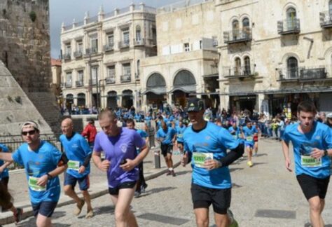 Läufer in Sportkleidung und einer Nummer auf dem Bauch laufe durch eine Stadt mit historischen Gebäuden