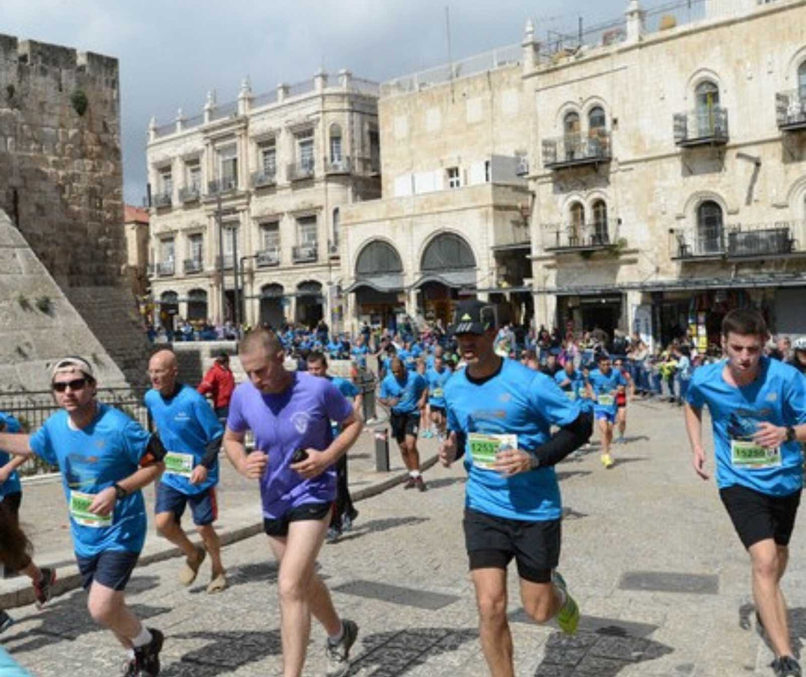 Läufer in Sportkleidung und einer Nummer auf dem Bauch laufe durch eine Stadt mit historischen Gebäuden