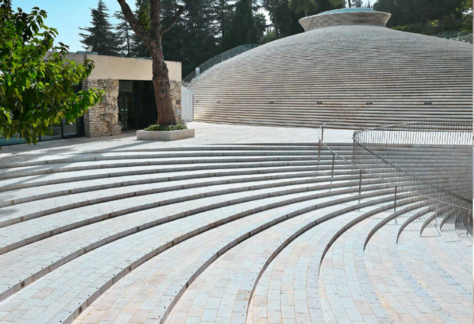 eine Anlage im Freien mit großen Treppen und einem anliegenden Gebäude mit treppenartiger Fassade. Im Hintergrund sind Bäume zu sehen.