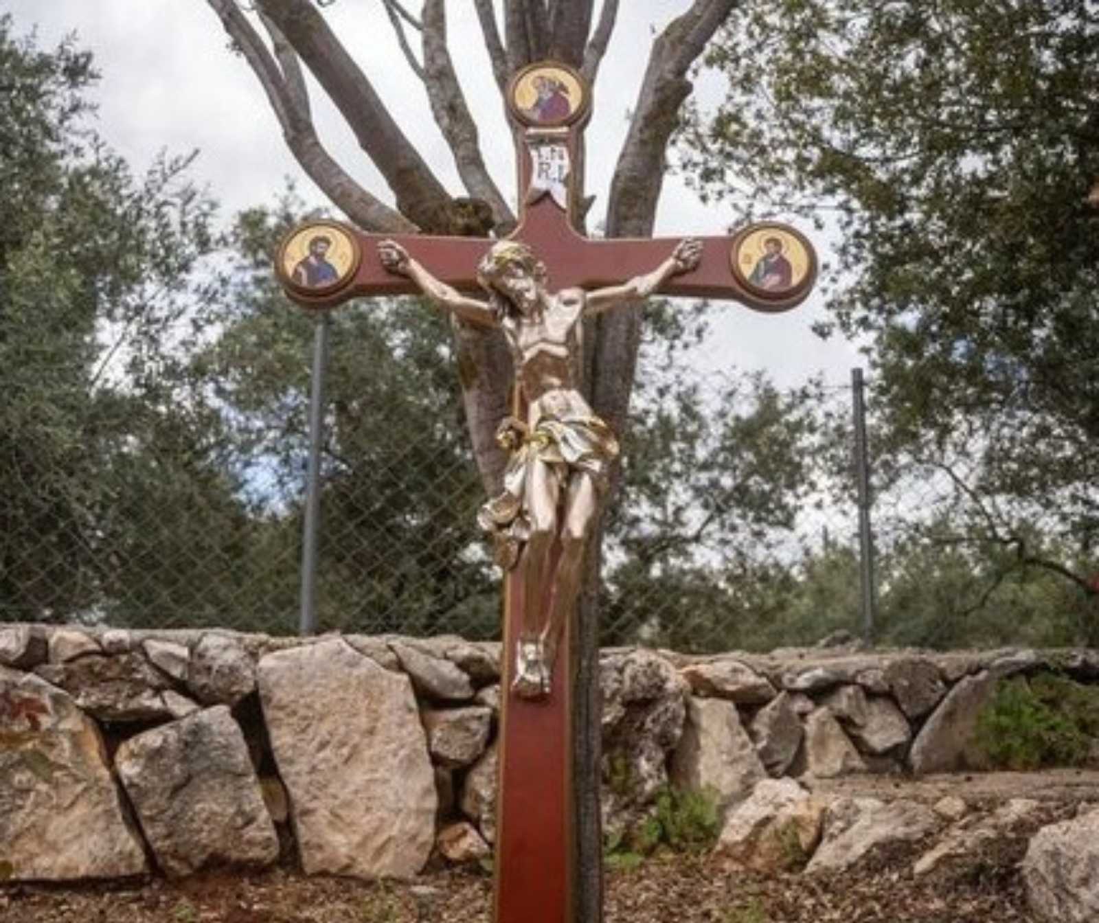 Ein Kruzifix in einee Außenanlage, vor einer Steinmauer stehend